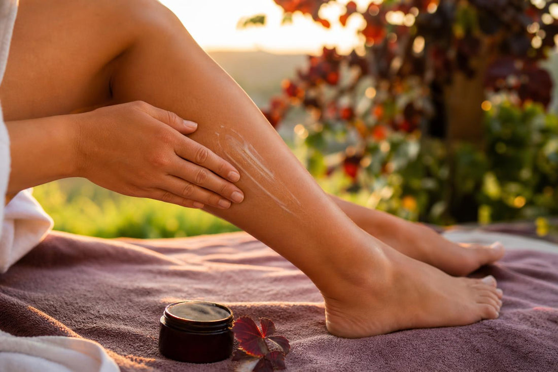 Massage du mollet en fin de journée avec application d’un baume sur peau intacte, ambiance naturelle et lumière chaude, évocation de la routine jambes lourdes.