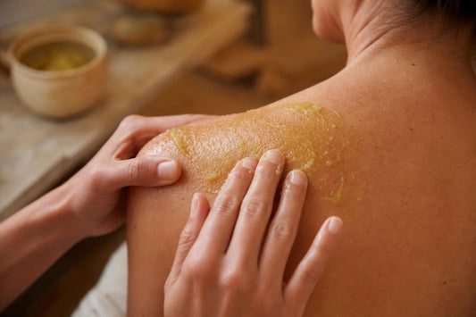 Mains appliquant un baume sur l’épaule pour soulager des douleurs musculaires, ambiance naturelle et artisanale, sans texte ni logo.